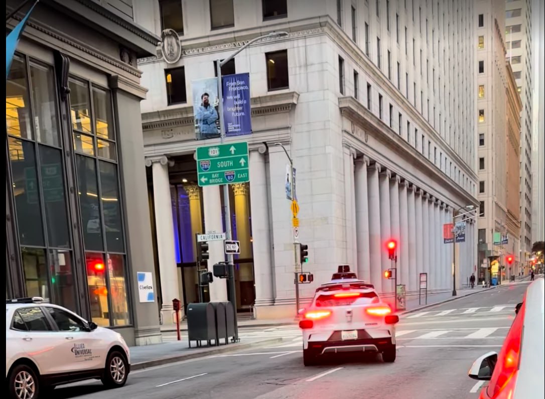 Waymo straddling two lanes at a red light